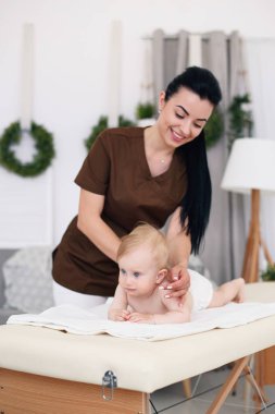 Profesyonel bayan masöz, küçük bir bebek için bir masaj yapar. Modern bir rahat oda içinde kanepede Çocuk Masaj.