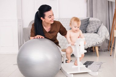 Nazik ve dostça çocuk Doktor oynayan küçük kız ile. Rahat oda ahşap oyuncak at üzerinde oyun gülümseyen küçük bebek.