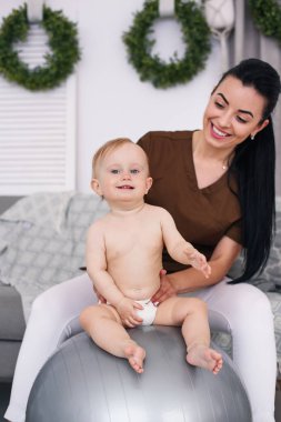 Fizyoterapist ile mutlu bebek Sağlık Odası, jimnastik topu ile yapıyor. Sağlık ve tıp kavramı.