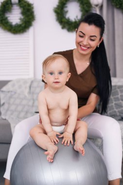 Fizyoterapist ile mutlu bebek Sağlık Odası, jimnastik topu ile yapıyor. Sağlık ve tıp kavramı.