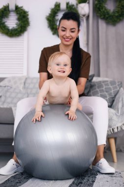 Fizyoterapist ile mutlu bebek Sağlık Odası, jimnastik topu ile yapıyor. Sağlık ve tıp kavramı.