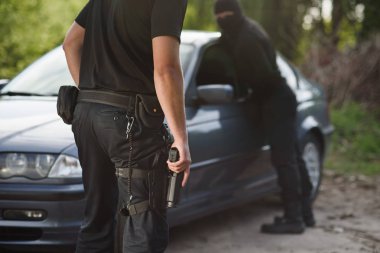 Bir polis elinde bir silah ile bir araba çalan bir suçlu tutuklandı. Hukuk ve adalet.