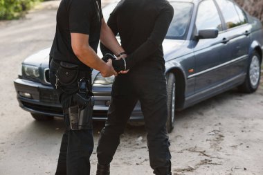 Bir polis memuru çalıntı araba ile bir suçlunun tutuklandı ve onu kelepçeli yakın.