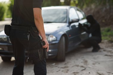 Bir polis elinde bir silah ile bir araba çalan bir suçlu tutuklandı. Hukuk ve adalet.