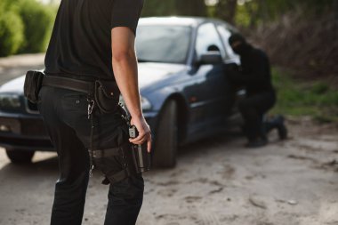 Bir polis elinde bir silah ile bir araba çalan bir suçlu tutuklandı. Hukuk ve adalet.