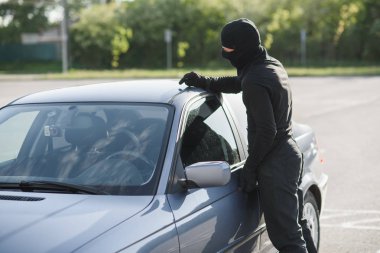 Bir suçlunun siyah kıyafet ve Maske alanlarındaki bir park yerinde bir araba çalmaya çalışıyor. Suçluluk durdurmak.