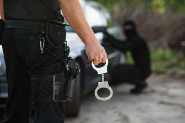 Onun elinde tutan kelepçeleri polis memuru. Polis arabayı çalan suçlu tutuklandı.