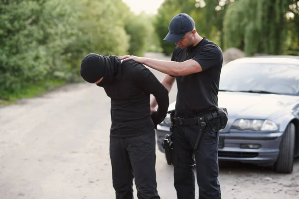 A police officer arrested an offender with the stolen car and handcuffed him close up.