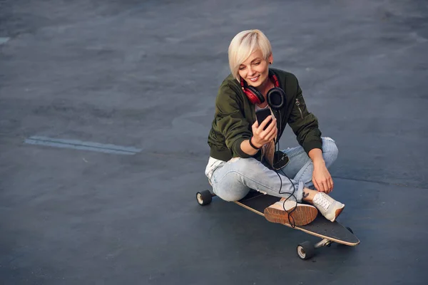 Joven Chica Rubia Sonriente Con Auriculares Usando Teléfono Inteligente Mientras — Foto de Stock