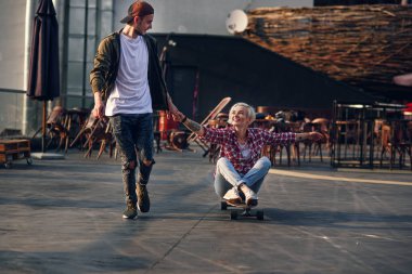 Yakışıklı genç çift kaykaylar endüstriyel binanın çatısında eğleniyor. Modern kentsel aktif yaşam tarzı kavramı.