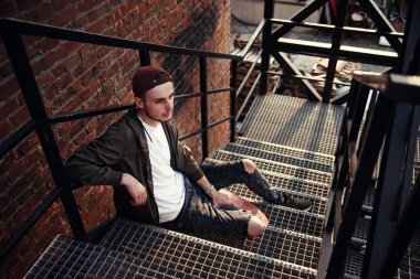 Genç yakışıklı hipster adam siyah demir merdiven endüstriyel bina kaykay ile.