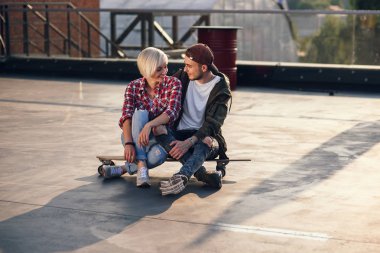 Genç güzel çift longboard eğleniyor endüstriyel binanın çatısına kaykay. Modern kentsel aktif yaşam tarzı kavramı.
