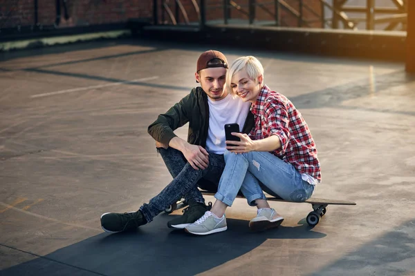 Bonito Casal Jovem Sentado Skate Longboard Telhado Edifício Industrial Fazendo — Fotografia de Stock