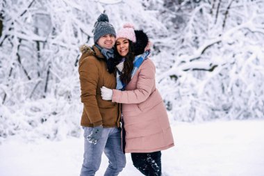 Karlı kış parkta güzel kocasıyla yürüyüş sıcak elbise giymiş güzel hamile kadın.