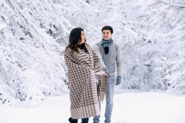 Mutlu güzel çift karlı bir parkta eğleniyor sıcak bir battaniye ile örtülü. Aile sevgi ve bakım kavramı.