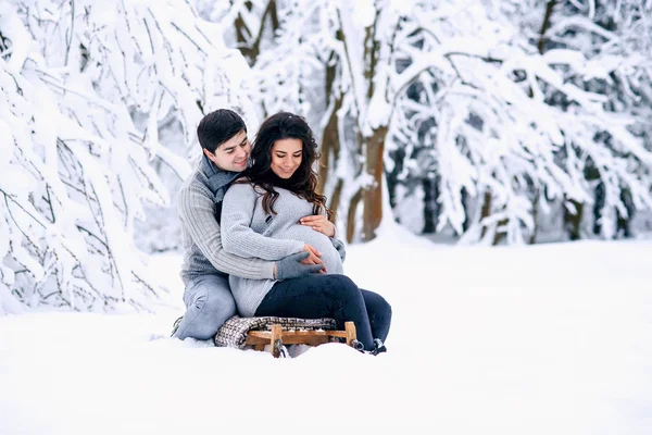 Piękna Kobieta Ciąży Mężem Siedząc Sankach Snowy Winter Park — Zdjęcie stockowe