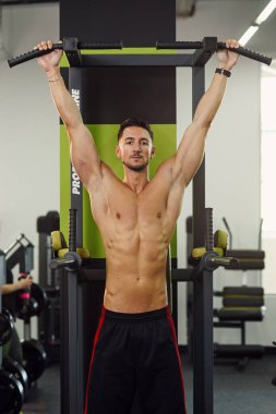 Güçlü çekici adam modern spor eğitim sırasında pull-up çubuk üzerinde yapar. Önden görünüm.