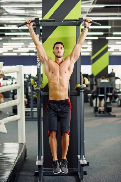 在现代健身房训练时 强壮有魅力的男人会在横梁上拉起身体 前视图 — 图库照片