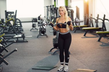 Pazı egzersiz halter salonunda ile yaparak atletik genç kadın. Sportif ve sağlıklı kavramı.