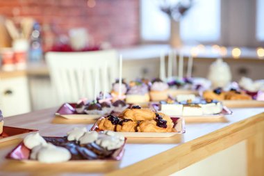 Lezzetli çikolata tatlı eklerleri ve ahşap masa ve tuğla duvar arka planda mor krem lezzetli kek. Tatil partisi konsepti.