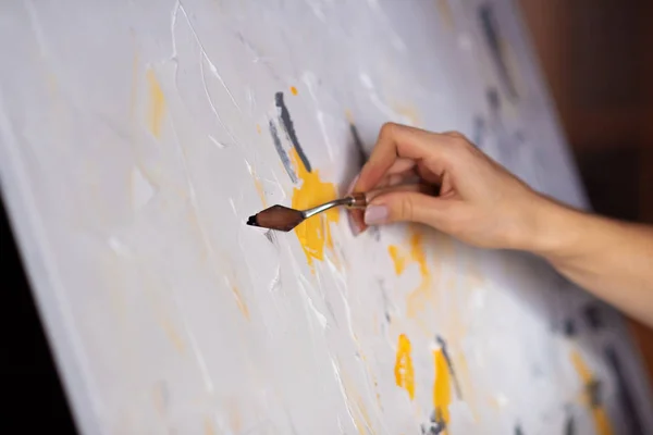 The artist\'s hand with mastic and paint slides on the canvas.