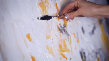 Sanatçının el Mastik ve sarı boya slaytlar beyaz tuval üzerine kapatın.