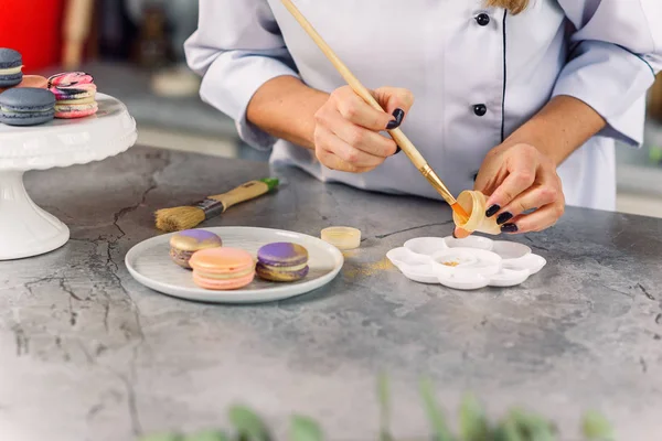 stock image Professional confectioner preparing food gold farb for painting fresh macarons.