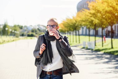 Genç beyaz ofis çalışanı ile eşarp yürüyüşler Ofis Binası yakınındaki iş başlamadan önce iş merkezi ve içecekler kahve yakınındaki bir gri ceketli. İş toplantısı için gidiş gözlüklü genç işadamı.