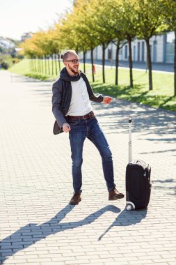 Çılgın ve mutlu bir genç işadamı açık havada başarı kutluyor ceketle dans ediyor. Ofis çalışanı, hafta sonu veya tatil, başarılı iş, iş, iş gezisi kavramı.