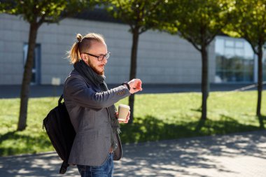 Genç başarılı iş adamı eşarp yürüyüşler ve iş merkezine yakın gri bir ceket kahve içiyor ve nöbetlere arıyorum. İş, bankacı, Yöneticisi kavramı.