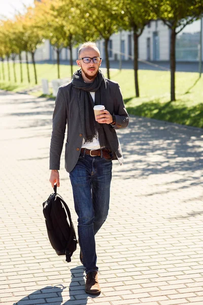 Yakışıklı ofis çalışanı bir çanta ve içecekler kahve sabah önce iş başlangıç ofis binası yakın tutan eşarp ile takım elbiseli. Genç işadamı iş toplantısına gidiyor.