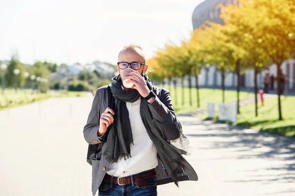 Genç beyaz ofis çalışanı ile eşarp yürüyüşler Ofis Binası yakınındaki iş başlamadan önce iş merkezi ve içecekler kahve yakınındaki bir gri ceketli. İş toplantısı için gidiş gözlüklü genç işadamı.