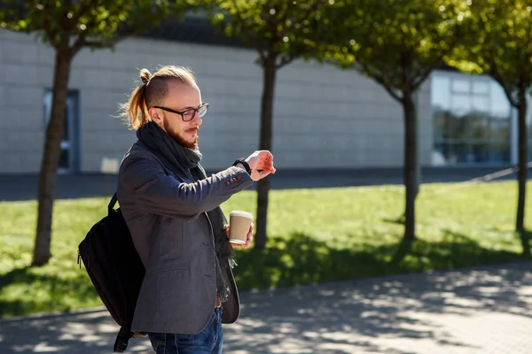 Genç başarılı iş adamı eşarp yürüyüşler ve iş merkezine yakın gri bir ceket kahve içiyor ve nöbetlere arıyorum. İş, bankacı, Yöneticisi kavramı.