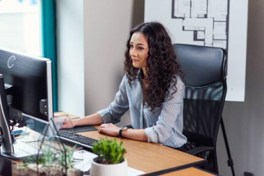 Modern ofis bilgisayarda çalışan genç iş kadını.