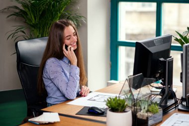 Kadın tasarımcı modern ofis akıllı telefonda konuşuyor. Güzel kız var bir iş istemci ile konuşmak.