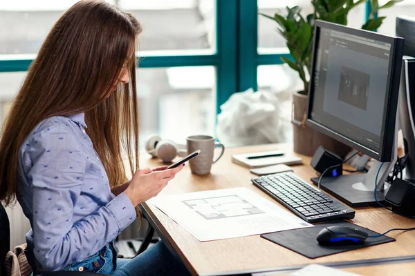 年轻的女建筑师在现代办公室的工作场所使用智能手机. — 图库照片