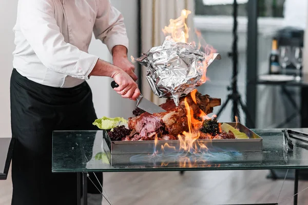 Chef cuts baked Turkey on a platter in the fire. Roast Turkey.