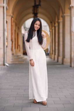 Ao Dai elbise kemerli arka plan karşı Vietnamca konik şapkalı güzel mutlu Asyalı kız giymiş.