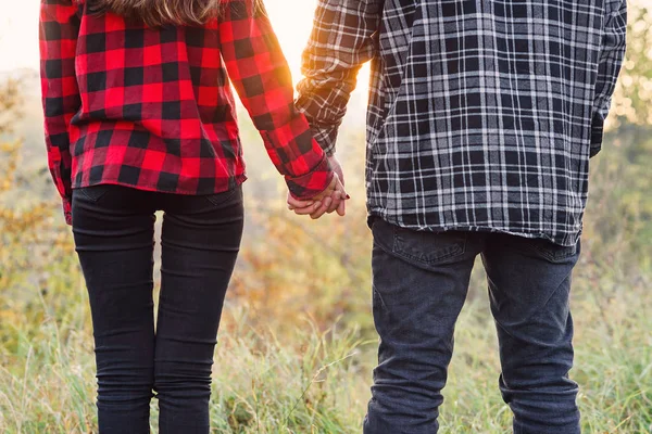 Stäng upp ung man och hans flickvän i casual kläder håller händerna till varandra. Lyckliga par med gitarr med resten om picknick i parken. — Stockfoto