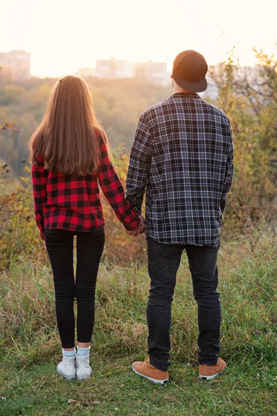 Close up jovem e sua namorada em roupas casuais mantém as mãos um para o outro. Casal feliz com guitarra tendo descanso em piquenique no parque . — Fotografia de Stock