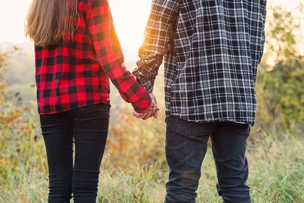 Close up young man and his girlfriend in casual clothes holds the hands to each other. Happy couple with guitar having rest on picnic in the park. — Stock Photo, Image