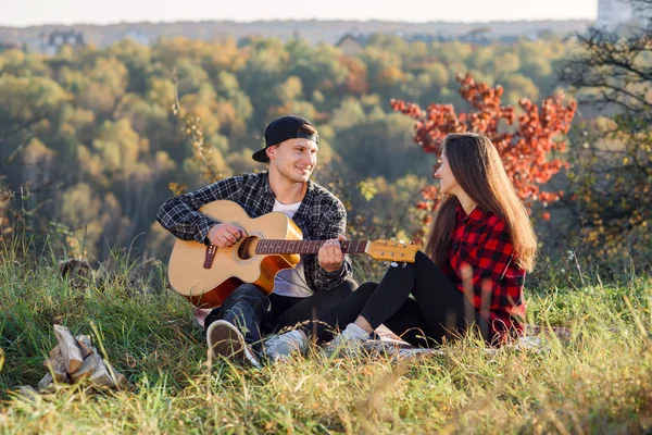 Lyckliga kaukasiska par med gitarr som vilar på picknick i parken — Stockfoto