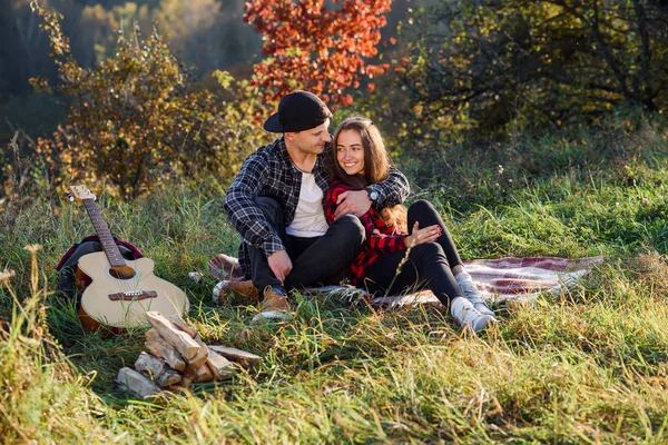 Feliz joven abraza a su novia ternura y descansar en el picnic en el parque. Pareja enamorada descansando al atardecer . — Foto de Stock