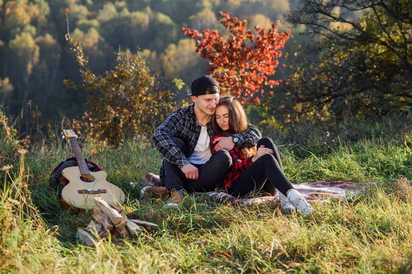 Feliz joven abraza a su novia ternura y descansar en el picnic en el parque. Pareja enamorada descansando al atardecer . — Foto de Stock