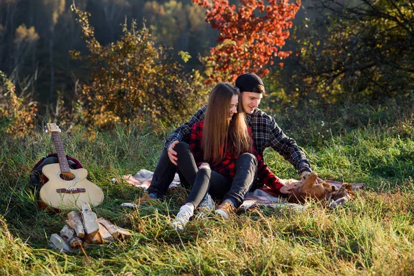 Felice coppia caucasica con chitarra a riposo su picnic nel parco primaverile. Giovane uomo e la sua ragazza giocare con il loro cane divertente . — Foto Stock