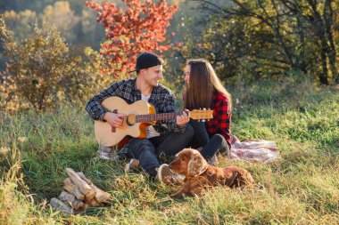 Mutlu çift gitar ve geri kalan çim Parkta piknik sahip onların köpek.