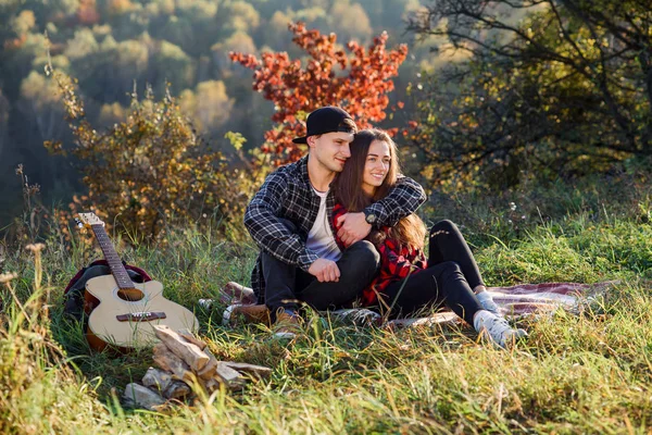 Glad ung man kramar sin flickvän ömhet och ha resten på picknick i parken. Par i kärlek med resten i solnedgången. — Stockfoto