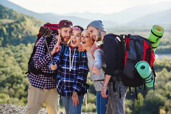Sommar resa koncept. Glada vänner som använder papperskarta nära hyrd bil i naturen. Glada resenärer i bergen på helgen semester. Vackra unga män och kvinnor hålla karta, utforska platsen på resan. — Stockfoto