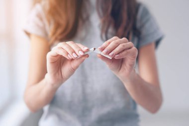 Kırık sigara elinde tutan güzel gülümseyen kız portresi. Mutlu kadın iş çıkışında sigara içmeyi. Kötü alışkanlık, sağlık kavramı çıkın. Sigara İçilmez.