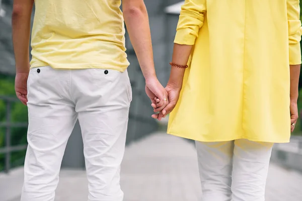 Close up jovem e sua namorada em roupas casuais mantém as mãos um para o outro. Vista de trás . — Fotografia de Stock